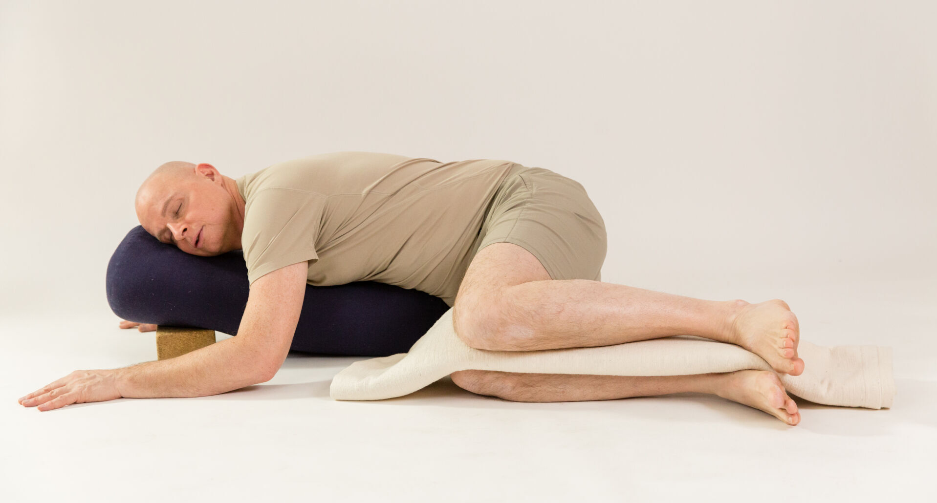 René Hug in Yin Yoga Haltung in Rückenlage mit Unterstützung von Bolstern